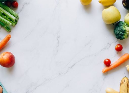 An assortment of fresh fruits and vegetables on a marble background, perfect for healthy lifestyle concepts.